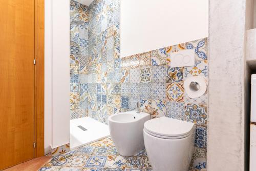 a bathroom with a toilet and tiles on the wall at Armandiola in Cardedu