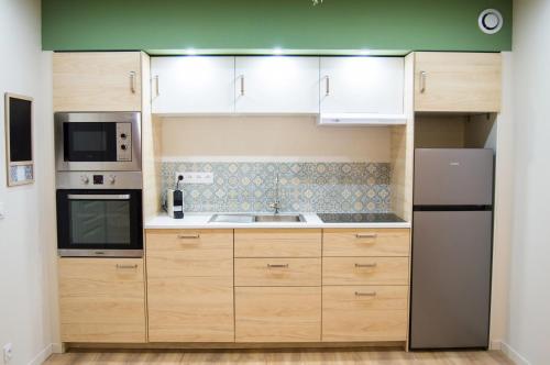 a kitchen with wooden cabinets and a stainless steel refrigerator at L'atelier vert - Suite Luxe, SPA, Proche Hypercentre - Classé 4 étoiles in Troyes