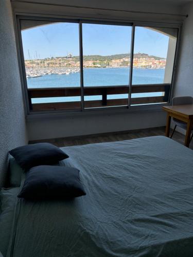 - une chambre dotée d'un lit avec des oreillers et d'une grande fenêtre dans l'établissement Studio cabine vue mer Agde Ile des pecheurs, au Cap d'Agde