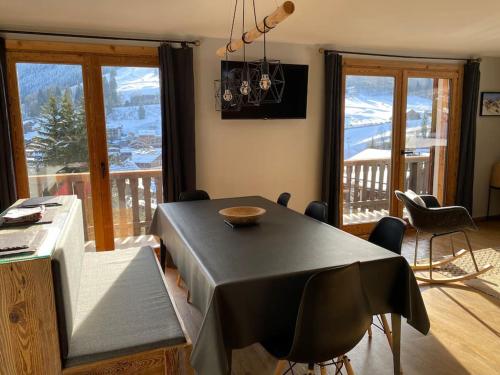 une salle à manger avec une table et un balcon dans l'établissement Appartement vieux Bois rénové avec terrasse, à La Clusaz