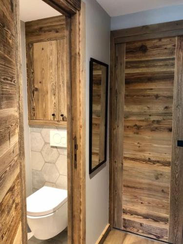 une salle de bain avec toilettes et porte en bois dans l'établissement Appartement vieux Bois rénové avec terrasse, à La Clusaz