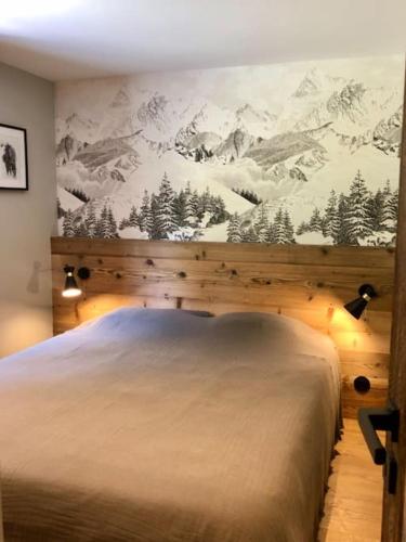 - une chambre avec un grand lit orné d'une fresque murale représentant la montagne dans l'établissement Appartement vieux Bois rénové avec terrasse, à La Clusaz