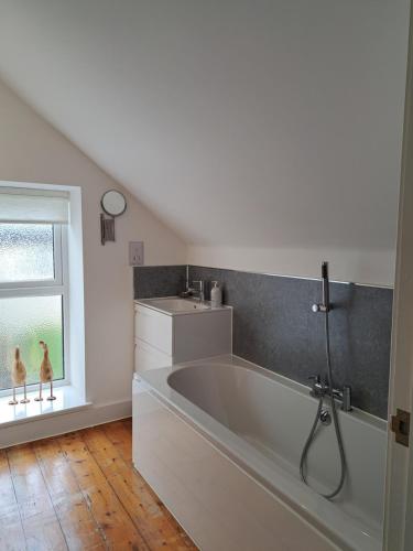 a large white tub in a bathroom with a window at Fig Cottage Holiday Home in Whitecroft