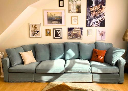 un divano blu in soggiorno con immagini appese al muro di Le Bohemian Chic - 4 chambres en hypercentre de Saint-Omer, idéal pour les groupes a Saint-Omer