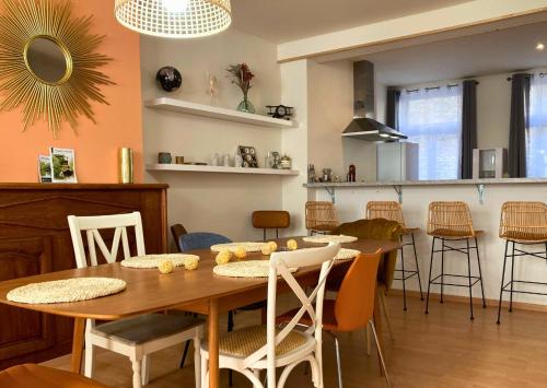 una sala da pranzo e una cucina con tavolo e sedie in legno di Le Bohemian Chic - 4 chambres en hypercentre de Saint-Omer, idéal pour les groupes a Saint-Omer