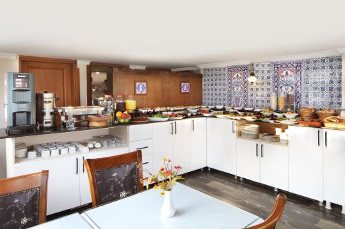 a large kitchen with white cabinets and a table at Aldem Hotel in Istanbul