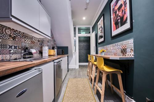 a kitchen with a bar with yellow chairs in it at Clarence House in Londonderry County Borough