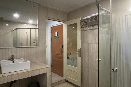 a bathroom with a sink and a shower and a mirror at Green Hero Darajat Hotel in Darajat