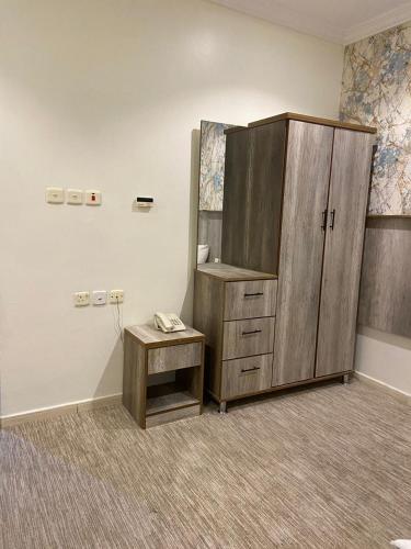 a room with a large wooden cabinet and a stool at فندق الخلفاء الفيصلية in Makkah
