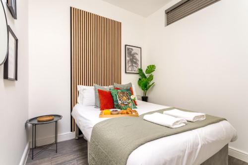 ブライトン＆ホーブにあるCozy Kingfisher - 2-Bed Bungalow in Brighton near the Beach With Free WiFi & Terrace by Kozmo Propertiesのベッドルーム1室(白いシーツとカラフルな枕が備わるベッド1台付)