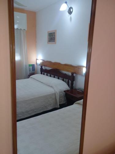 a mirror in a bedroom with two beds at Dennisse Hotel in Victoria