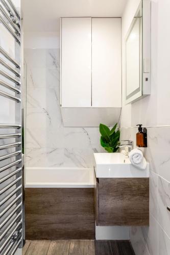 a bathroom with a white tub and a sink at Cozy Kingfisher - 2-Bed Bungalow in Brighton near the Beach With Free WiFi & Terrace by Kozmo Properties in Brighton & Hove