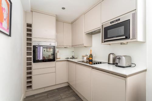 a kitchen with white cabinets and a microwave at Cozy Kingfisher - 2-Bed Bungalow in Brighton near the Beach With Free WiFi & Terrace by Kozmo Properties in Brighton & Hove