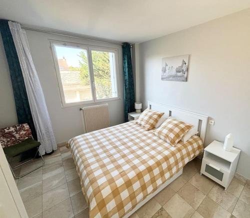 a bedroom with a bed with a plaid blanket and a window at Appartement chaleureux avec balcon - Champigny in Champigny-sur-Marne