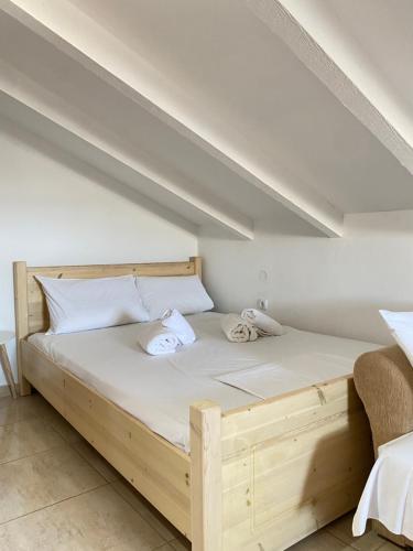 a bedroom with a wooden bed with white sheets at Villa Elva in Ammoudia