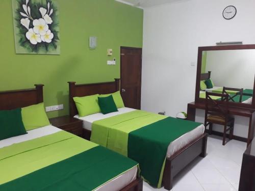Grünes Zimmer mit 2 Betten und einem Spiegel in der Unterkunft Sunshine Holiday Resort -Sella Kataragama in Kataragama
