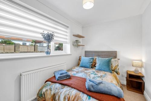 a bedroom with a bed with blue pillows and a window at Minutes from the port of Dover, free WiFi, free offroad private parking and rated a guest favourite on Air b nb! in Kent