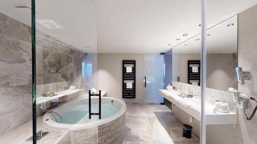 a bathroom with two sinks and a bath tub at Van der Valk Hotel Mons Congres & Spa in Mons