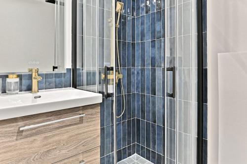 une salle de bain avec un lavabo et une douche avec du carrelage bleu dans l'établissement Appartement 3 chambres Paris 2ème - II, à Paris