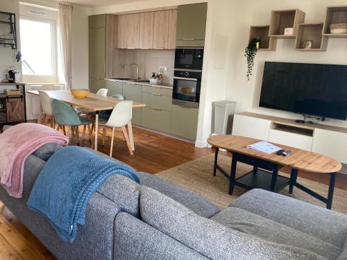 un salon avec un canapé et une table et une cuisine dans l'établissement L'escale Donvillaise, à Donville-les-Bains