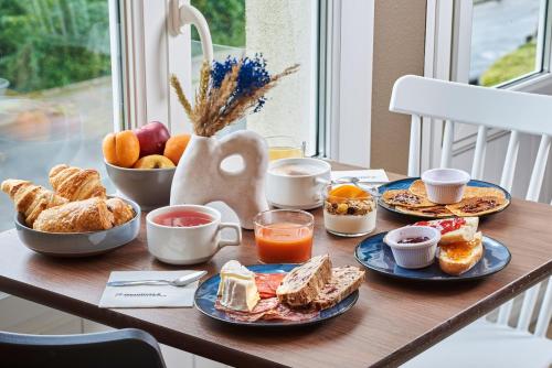 a table with plates of breakfast food on it at The Originals City, Hôtel A Pic, Cherbourg in Cherbourg en Cotentin