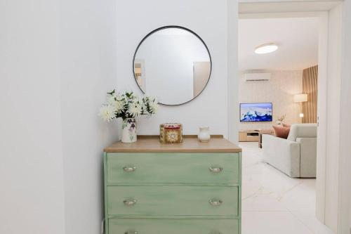 a green dresser in a living room with a mirror at Spinola Court 2bed W Pool And Parking By Homely in Tal-Għoqod