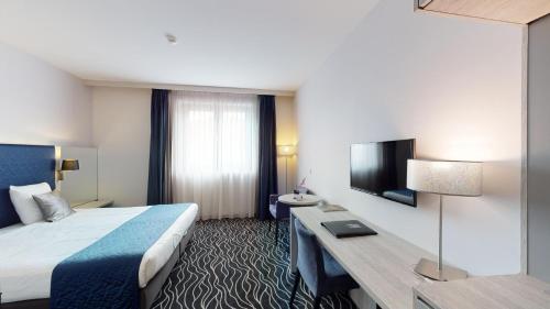 a hotel room with a bed and a television at Van der Valk Hotel Mons Congres & Spa in Mons