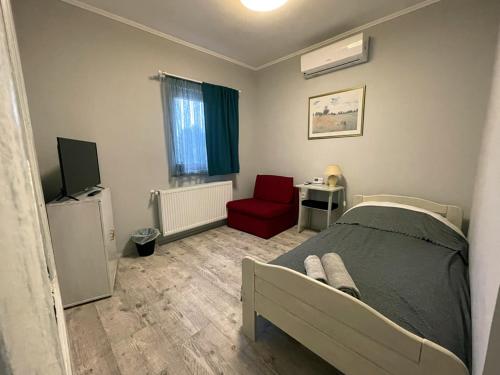 a bedroom with a bed and a red chair at Ulics vendégház II in Zalacsány