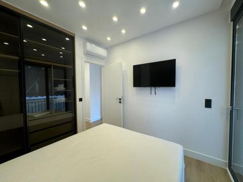 a white bedroom with a flat screen tv on the wall at BlueMotion - PortSuite 4A in Piraeus