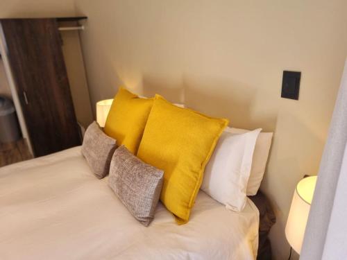 a bed with yellow and white pillows on it at On-the-Up at Molen in Potchefstroom