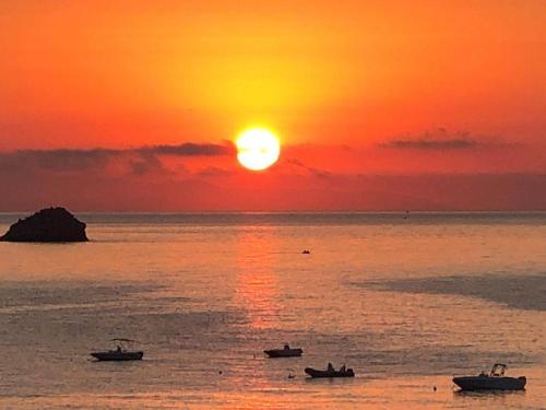 una puesta de sol sobre el océano con barcos en el agua en Taormina wonderful seaview, en Giardini Naxos