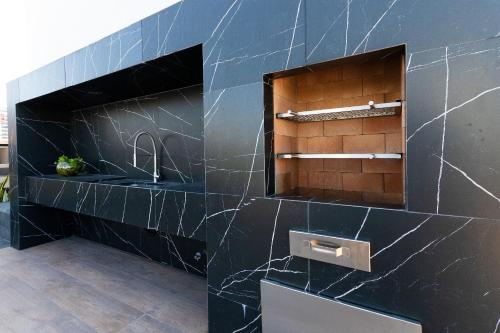 a bathroom with a black tiled wall with a sink at Way Tambaú #J2 - Triplo deluxe por Carpediem in Tambaú