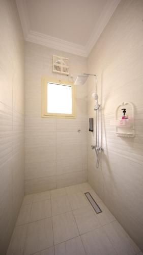a white bathroom with a shower and a window at Stay easy Obhur - ستاي ايزي in Obhor