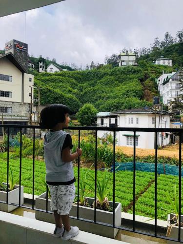 a young child standing on a balcony looking out at a garden at R21 Nuwara Eliya in Nuwara Eliya