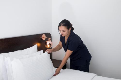 a woman standing over a bed with pillows at Hotel Acqua Medellín in Medellín