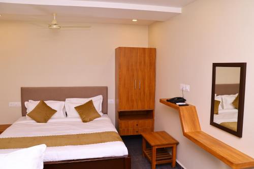 a small bedroom with a bed and a mirror at JSN Grand in Srikalahasti