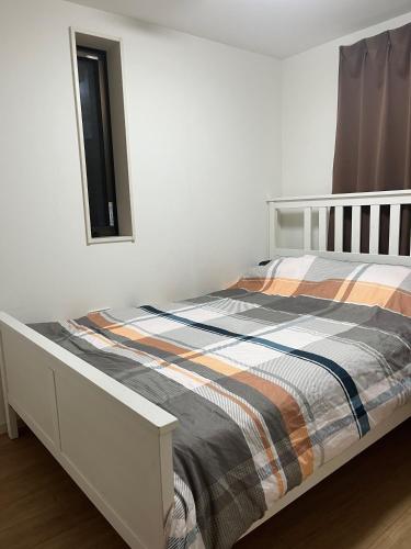 1 dormitorio con cama blanca y manta a rayas en Miaoyi Asakusa, en Tokio