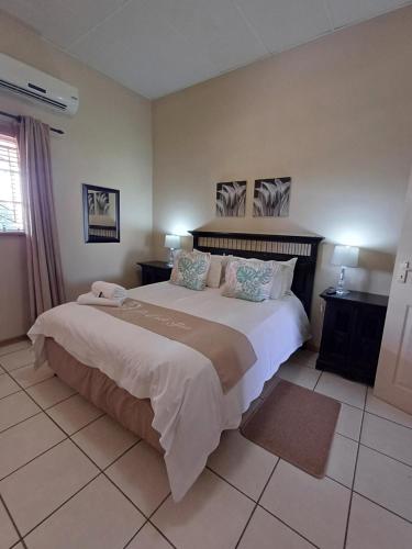 a bedroom with a large white bed with two night stands at Augrabies De Oude Stoor Guesthouse in Augrabies