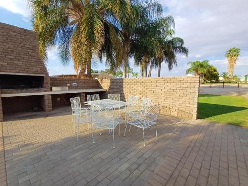 a table and chairs on a patio with palm trees at Augrabies De Oude Stoor Guesthouse in Augrabies