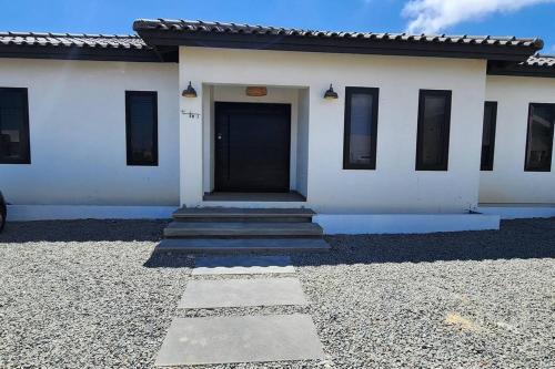 a white building with a black door on it at Los Cosos Mansion - Sleep 6 in Palm-Eagle Beach