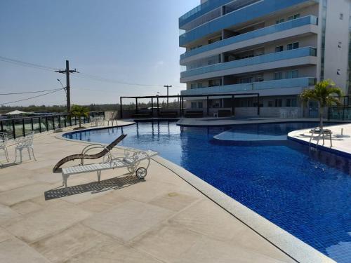 Una piscina con un banco delante de un edificio. en Le Bon Vivant 307 B, en Arraial do Cabo