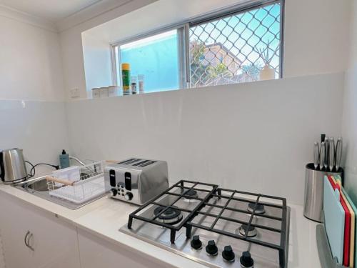 a kitchen with a stove and a microwave at Comfy unit near Garden City Westfield Street Parking in Brisbane