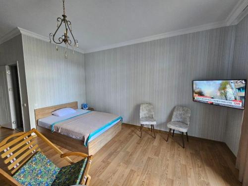 Un dormitorio con una cama y dos sillas y un televisor. en Квартира, en Batumi