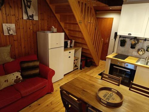 a living room with a red couch and a kitchen at Charmant Chalet de montagne in Picherande