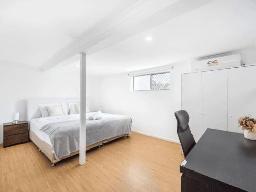 a white bedroom with a bed and a desk at 1 Bedroom Unit near Highway Transports n Shops in Brisbane