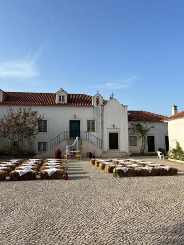 a large white building with bales of hay in a courtyard at Santuário SOS Animal in Casais da Carneiria