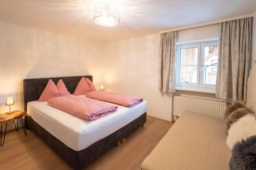 a bedroom with a bed with red pillows and a window at Bramsauerhof in Faistenau