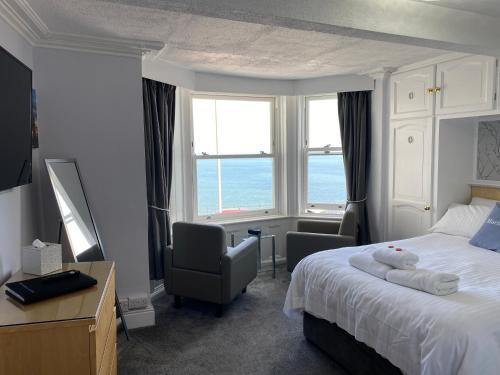 a hotel room with a bed and chairs and a window at Marine View Guest House in Scarborough