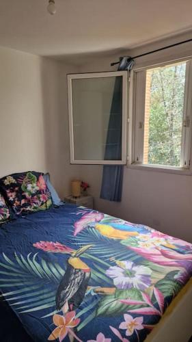 une chambre avec un lit avec une couette colorée et une fenêtre dans l'établissement Joli T2 vue sur le jardin proche de Toulouse, à Launaguet