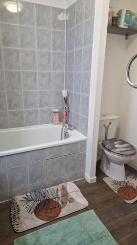 La salle de bains est pourvue d'une baignoire, de toilettes et d'un tapis. dans l'établissement Joli T2 vue sur le jardin proche de Toulouse, à Launaguet
